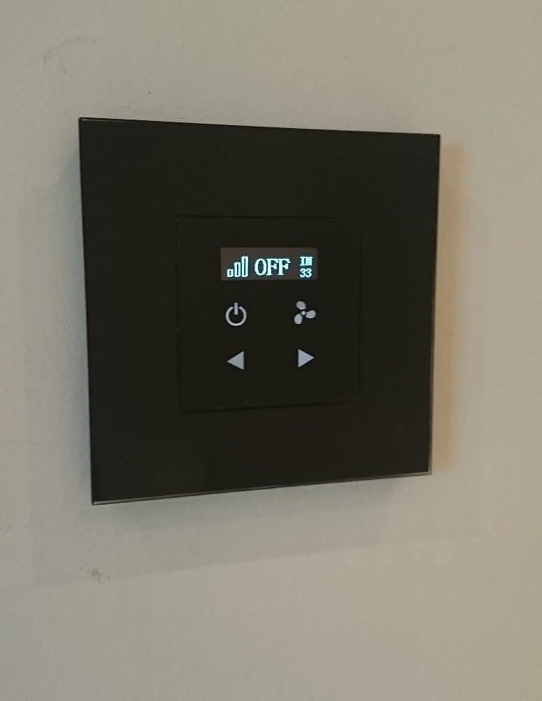 A matte black climate control panel mounted flush to the wall