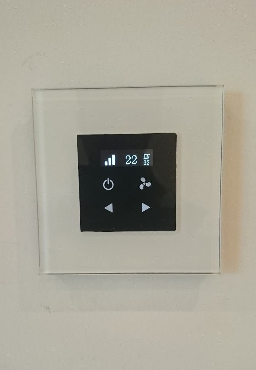 A glass-fronted white climate control panel